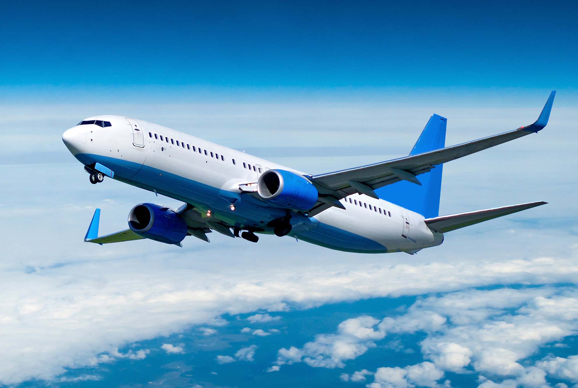 Home Page JetV2 1982x1333px A blue & white commercial airline in flight just after takeoff. Ascending through a blue but cloudy sky