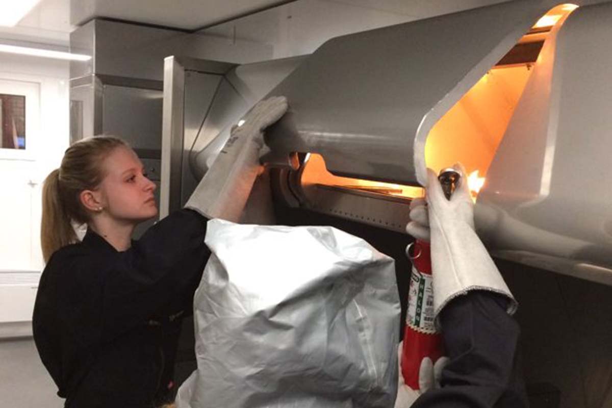 Real firefighter simulator with crew training extinguishing a fire in the overhead luggage compartment of a plane